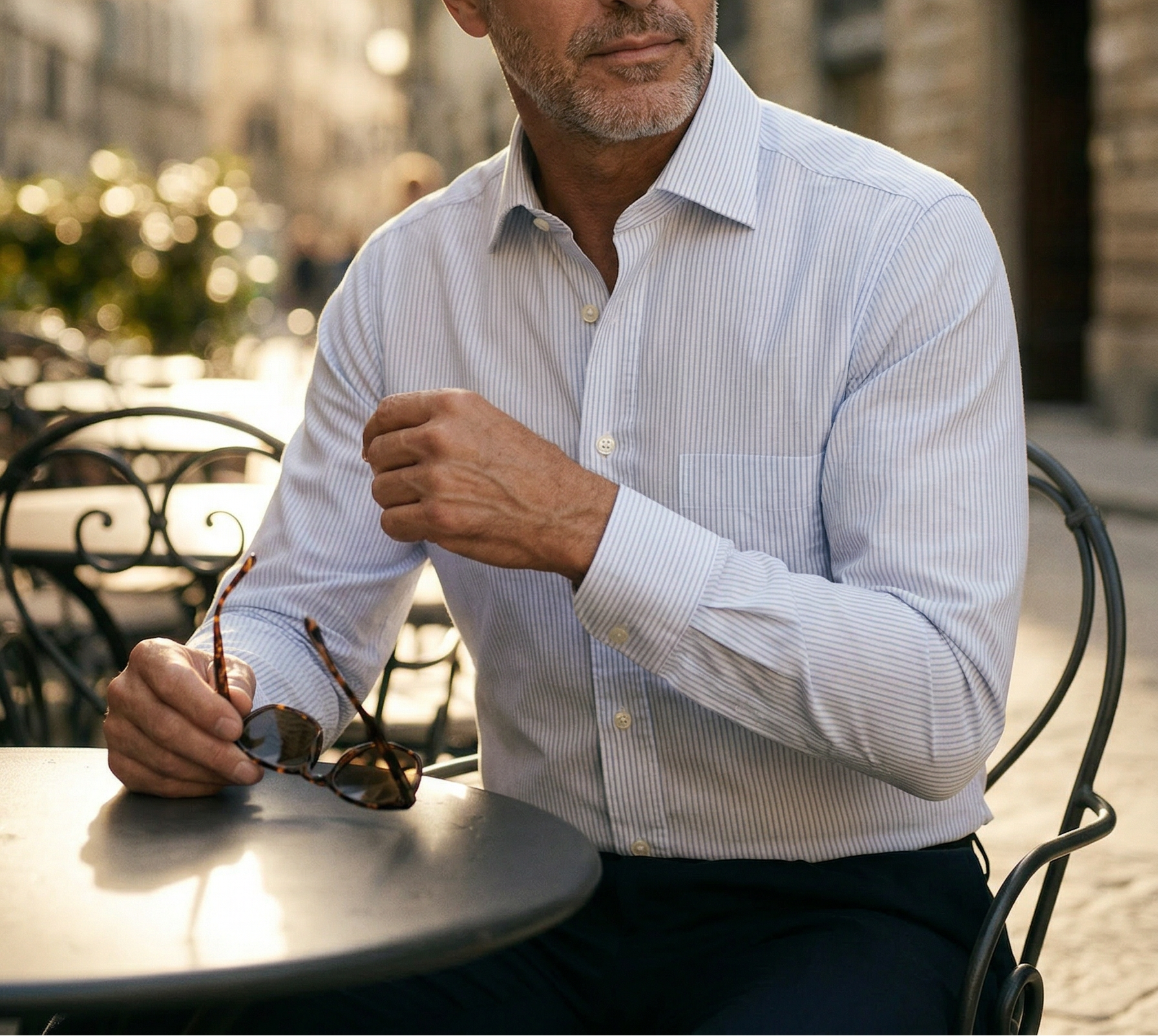 Man sitting outdoors in an urban setting wearing a light blue shirt.